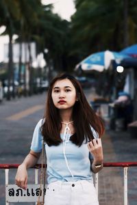 Portrait of young woman standing against city in background