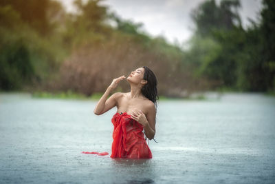 Woman with red umbrella standing in water