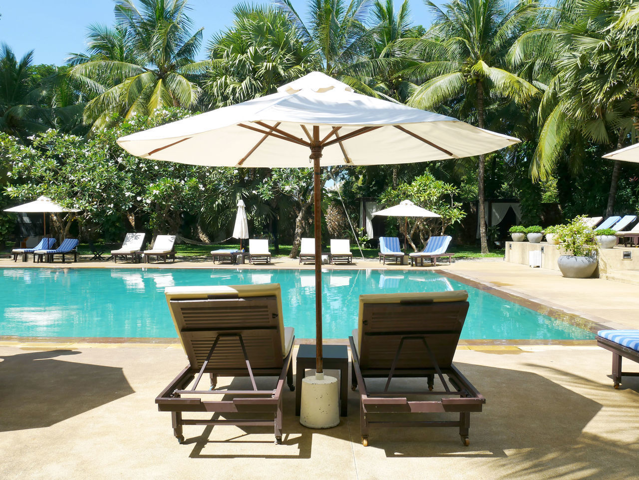 LOUNGE CHAIRS BY SWIMMING POOL AT RESORT