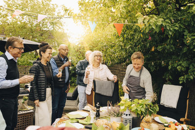 Cheerful senior friends enjoying during back yard dinner party