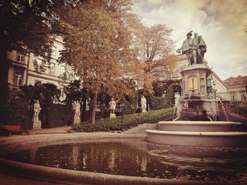 Fountain by trees against sky