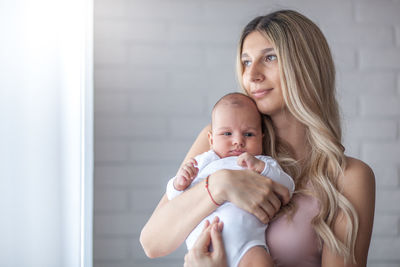 Smiling mother holding baby boy at home