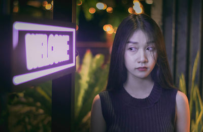 Woman looking at illuminated welcome sign