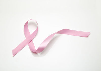 Close-up of breast cancer awareness ribbon over white background