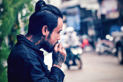 Side view of young man looking away in city