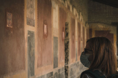 Side view of young woman standing against wall