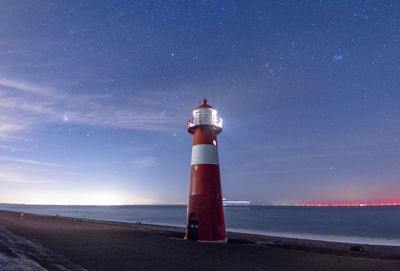 Lighthouse by sea against sky