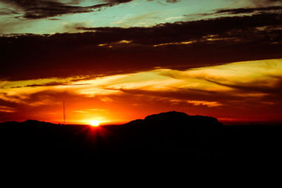 Sun shining through clouds over mountains