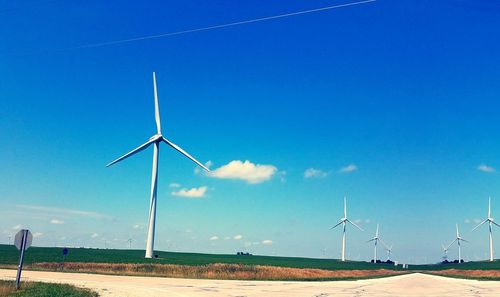 Wind turbines on field against blue sky