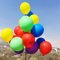 Multi colored balloons flying against blue sky