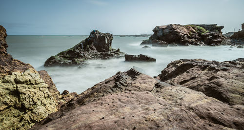 Scenic view of rocky beach against sky