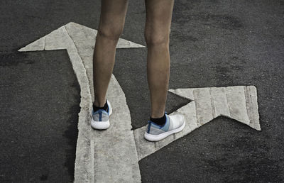 Low section of woman standing on road