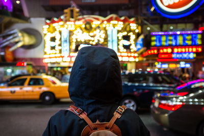 Woman standing on illuminated city street at night