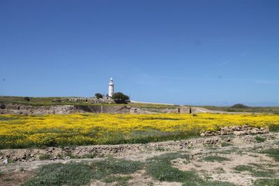 Lighthouse on landscape against clear blue sky