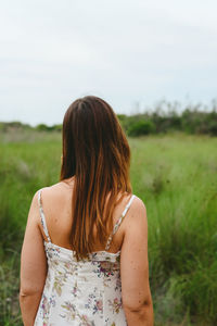 Rear view of woman standing on field against sky