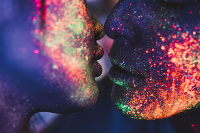 Close-up of couple with multi colored face paint kissing