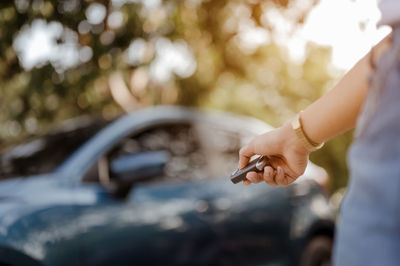 Midsection of woman locking car door outdoors