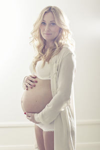 Portrait of pregnant woman holding abdomen at home