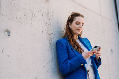 Modern businesswoman in blue suit using mobile phone. copyspace