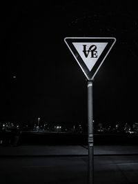 Illuminated information sign against sky at night