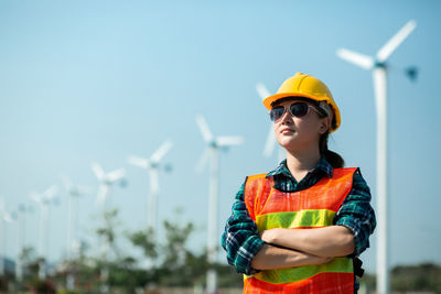 Young woman wearing sunglasses standing against sky