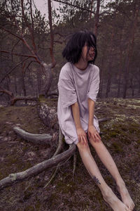 Woman sitting on tree trunk in forest