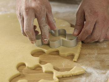 Cropped hands of chef cutting dough with pastry cutter at table