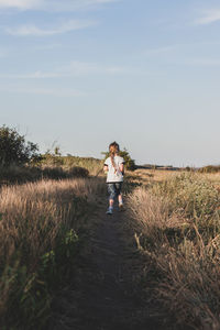 Woman standing on field against sky