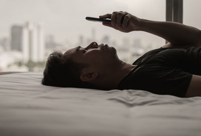 Asian man feels sad on bed looking and focus on smartphone. mental health concept.