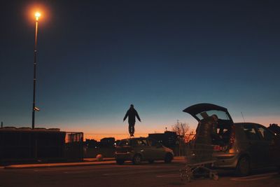 Man jumping on road against sky during sunset