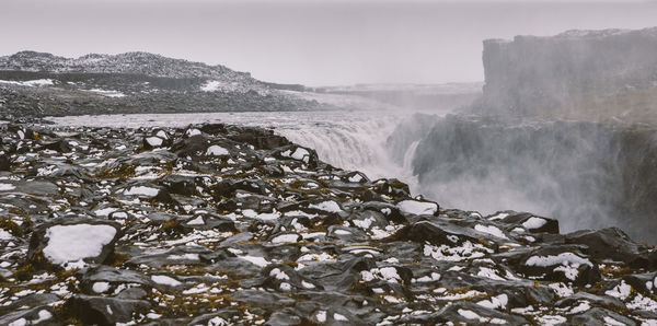 Scenic view of waterfall against sky during winter