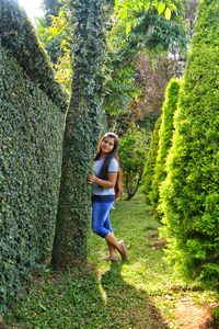 Full length portrait of smiling young woman against tree