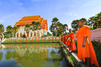 Panoramic view of temple by lake against sky