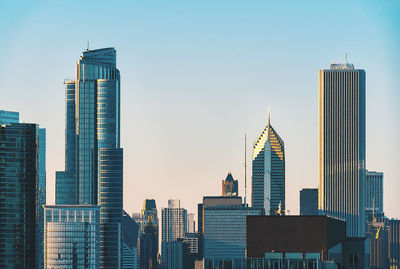 Modern buildings in city against clear sky during sunset