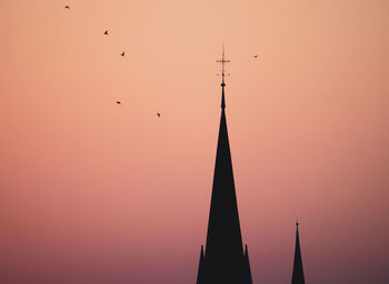 Low angle view of silhouette birds flying against sky during sunset