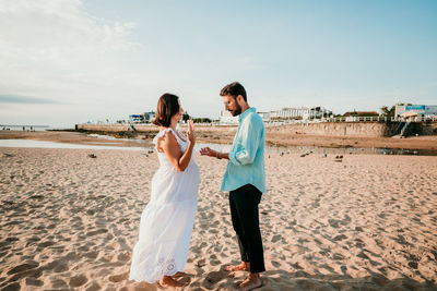 Friends standing on beach against sky