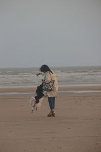 Rear view of woman standing at beach against clear sky