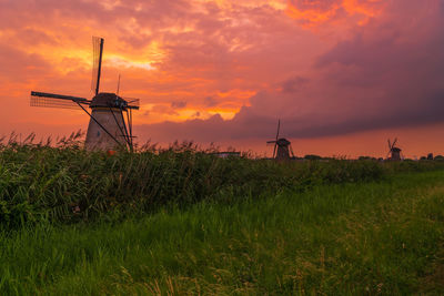 Windmills on field against sky during sunset