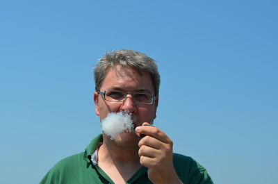 Close-up of man smoking pipe against sky