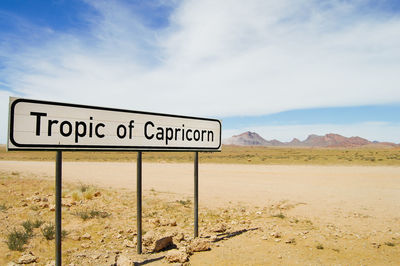 Information sign on desert against sky