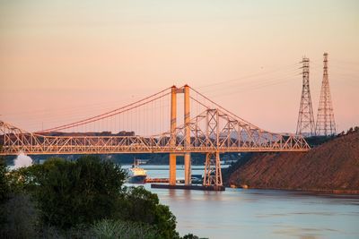 Suspension bridge over river against sky