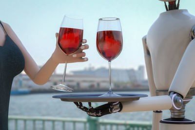 Mannequins with wineglasses against sky