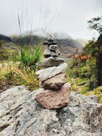 Stack of stones on field against sky