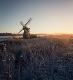 Traditional windmill on field against clear sky