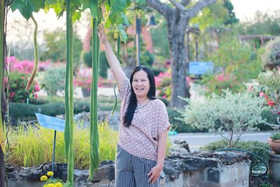 Portrait of young woman standing against plants