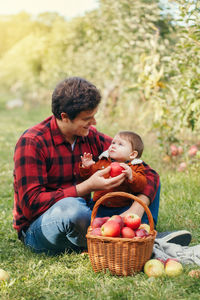 Father showing apple to son at forest