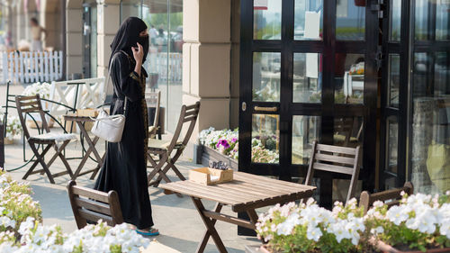 A muslim woman national dress walks past empty tables in a cafe.