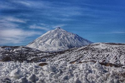 Scenic view of snowcapped mountains against blue sky