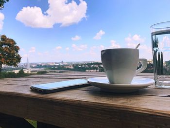 Coffee cup on table against sky