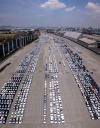 Aerial logistics commercial vehicles waiting to be load on to a car carrier ship at dockyard